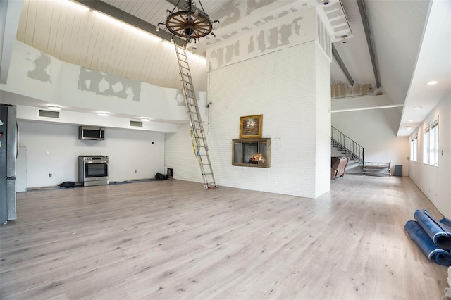 9938 Alavista Dr, Gibsonton, FL 33534 - unfurnished living room featuring high vaulted ceiling, stairs, a fireplace, wood finished floors, and beam ceiling