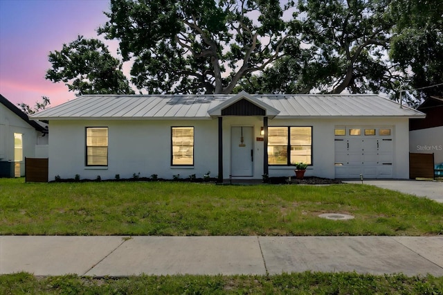 706 E Gate Dr, Safety Harbor, FL 34695 - view of front facade featuring a standing seam roof, stucco siding, an attached garage, and a front lawn