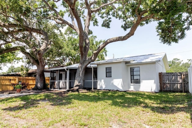706 E Gate Dr, Safety Harbor, FL 34695 - back of house with stucco siding, a sunroom, and a fenced backyard