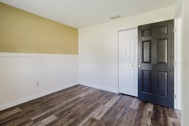 706 E Gate Dr, Safety Harbor, FL 34695 - unfurnished bedroom with dark wood finished floors, a closet, and a wainscoted wall