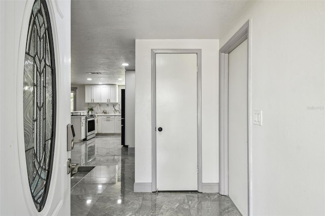 6200 13th Ave, New Port Richey, FL 34653 - hallway with marble tiled floors, a textured ceiling, and recessed lighting