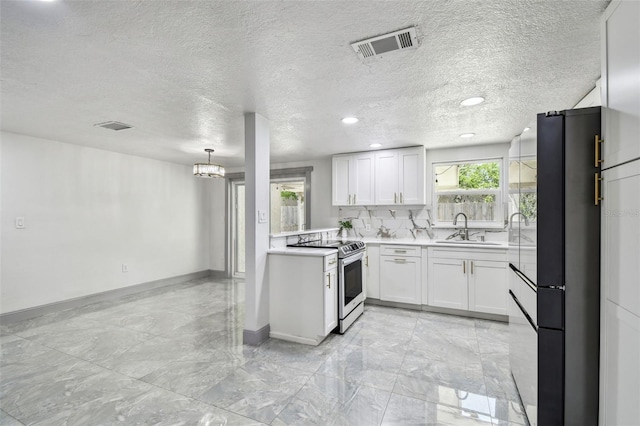 6200 13th Ave, New Port Richey, FL 34653 - kitchen with stainless steel range with electric cooktop, freestanding refrigerator, light countertops, a chandelier, and white cabinets