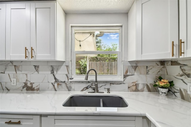 6200 13th Ave, New Port Richey, FL 34653 - kitchen featuring white cabinetry, a textured ceiling, light stone counters, and backsplash