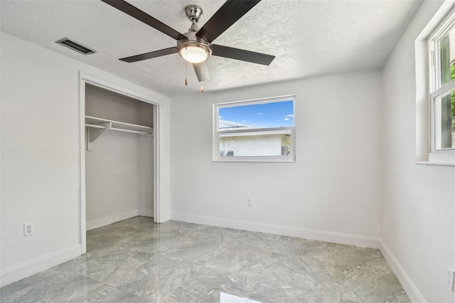 6200 13th Ave, New Port Richey, FL 34653 - unfurnished bedroom with a textured ceiling, multiple windows, a closet, and a ceiling fan