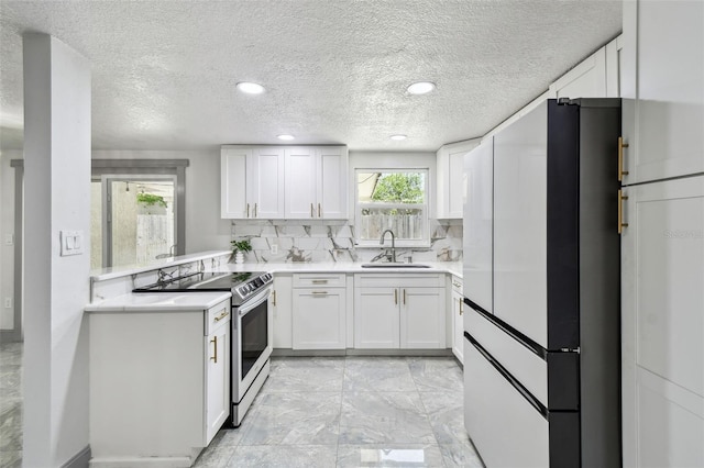 6200 13th Ave, New Port Richey, FL 34653 - kitchen with stainless steel range with electric cooktop, freestanding refrigerator, light countertops, white cabinets, and decorative backsplash