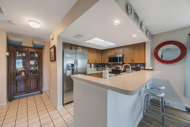 9205 Jakes Path, Largo, FL 33771 - kitchen with appliances with stainless steel finishes, light countertops, a peninsula, a breakfast bar area, and decorative backsplash