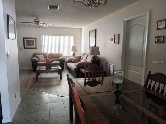 432 Flamingo Dr, Apollo Beach, FL 33572 - dining space with dark tile patterned flooring, ceiling fan, a chandelier, and a textured ceiling
