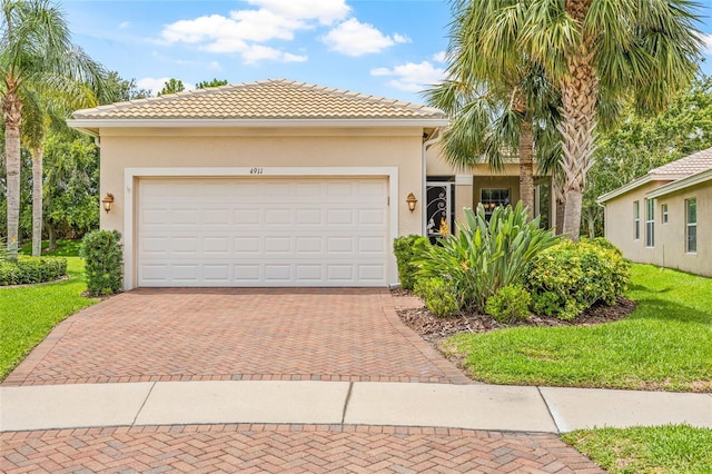 4911 Rock Island Ct, Wimauma, FL 33598 - view of front of property with decorative driveway, stucco siding, a front lawn, a tile roof, and an attached garage