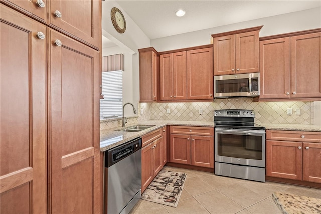 4911 Rock Island Ct, Wimauma, FL 33598 - kitchen featuring appliances with stainless steel finishes, light tile patterned flooring, light stone counters, decorative backsplash, and brown cabinetry