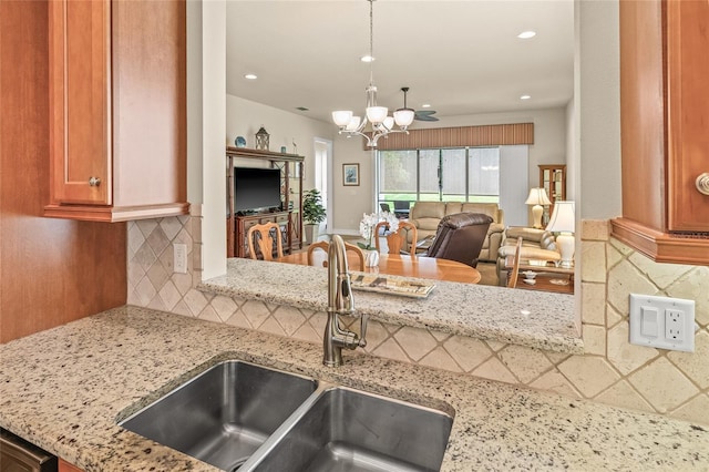 4911 Rock Island Ct, Wimauma, FL 33598 - kitchen featuring light stone countertops, decorative backsplash, a chandelier, recessed lighting, and open floor plan