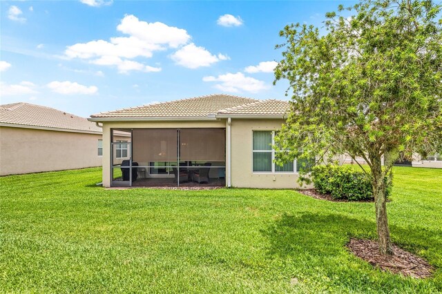 4911 Rock Island Ct, Wimauma, FL 33598 - rear view of property featuring a tiled roof, a lawn, stucco siding, and a sunroom