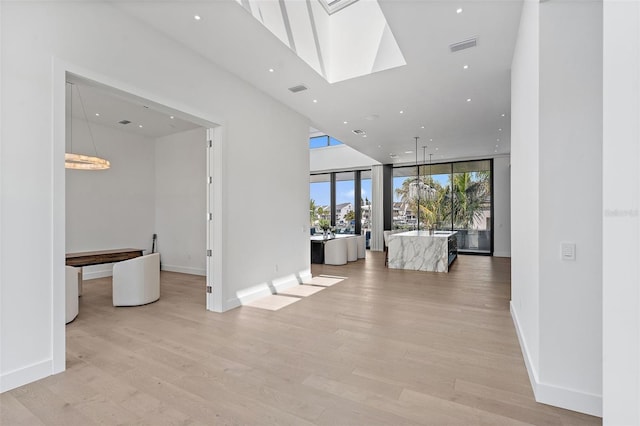 501 Barcelona Dr, Tierra Verde, FL 33715 - unfurnished living room with light wood finished floors, a wall of windows, recessed lighting, and a skylight