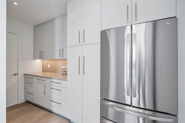 501 Barcelona Dr, Tierra Verde, FL 33715 - kitchen featuring freestanding refrigerator, light countertops, light wood finished floors, and white cabinets