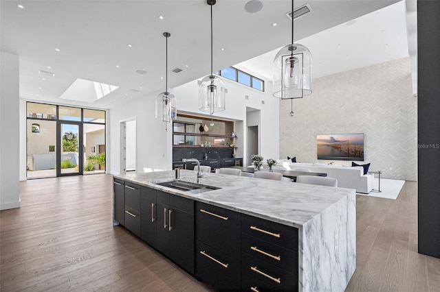 501 Barcelona Dr, Tierra Verde, FL 33715 - kitchen with open floor plan, dark cabinets, an accent wall, a skylight, and a towering ceiling
