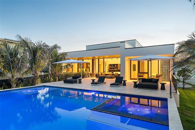 501 Barcelona Dr, Tierra Verde, FL 33715 - back of house at dusk with an outdoor hangout area, a hot tub, a patio, and stucco siding
