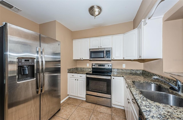 2003 Whispering Pines St, Largo, FL 33774 - kitchen featuring appliances with stainless steel finishes, white cabinets, light tile patterned floors, and dark stone countertops