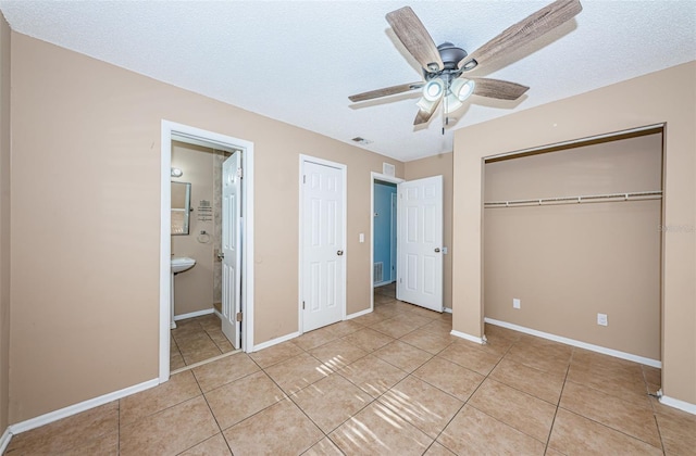 2003 Whispering Pines St, Largo, FL 33774 - unfurnished bedroom featuring light tile patterned floors, a textured ceiling, ensuite bathroom, and a ceiling fan