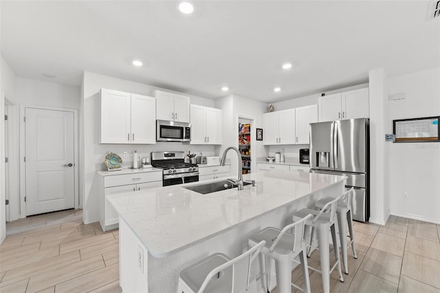 9815 Carabiner Way, Land O Lakes, FL 34637 - kitchen featuring stainless steel appliances, a kitchen bar, white cabinetry, a kitchen island with sink, and recessed lighting