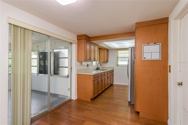 3547 Morley Dr, New Port Richey, FL 34652 - kitchen with dark wood-style flooring, light countertops, freestanding refrigerator, and brown cabinets