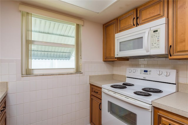 3547 Morley Dr, New Port Richey, FL 34652 - kitchen with white appliances, brown cabinets, light countertops, tile walls, and a wainscoted wall