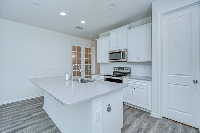 11619 Cambium Crown Dr, Riverview, FL 33569 - kitchen featuring stainless steel appliances, french doors, an island with sink, light wood-style flooring, and decorative backsplash