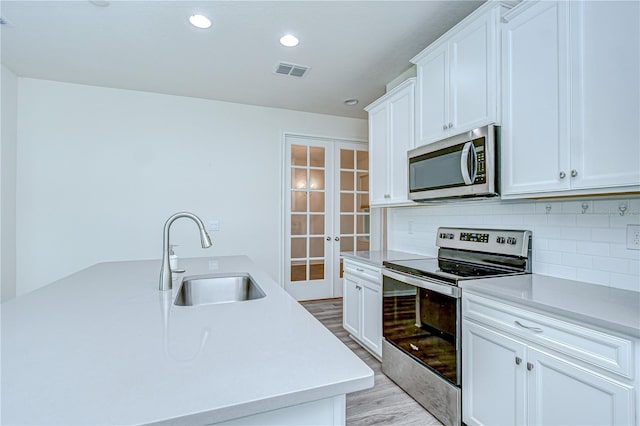11619 Cambium Crown Dr, Riverview, FL 33569 - kitchen featuring appliances with stainless steel finishes, french doors, light wood-style flooring, backsplash, and light countertops
