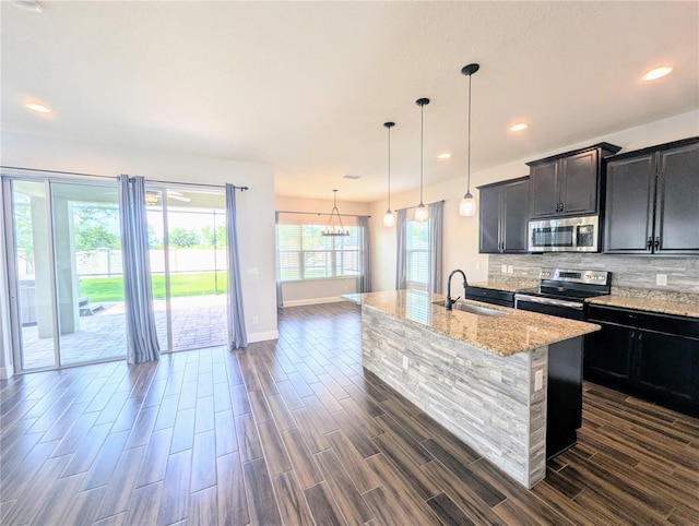 32599 Natural Bridge Rd, Wesley Chapel, FL 33543 - kitchen with stainless steel appliances, backsplash, dark wood-style flooring, an island with sink, and light stone countertops