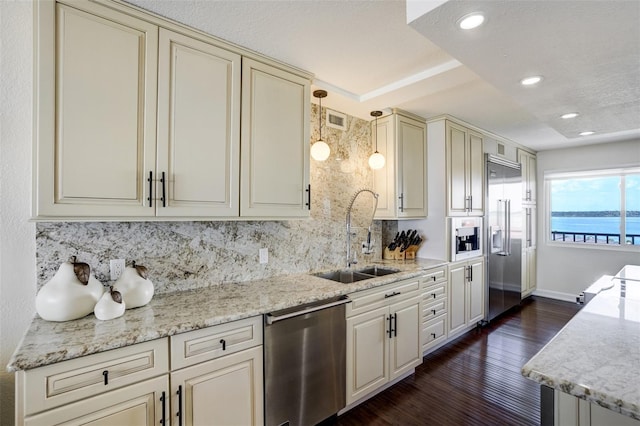 1581 Gulf Blvd Unit 701N, Clearwater Beach, FL 33767 - kitchen featuring stainless steel appliances, cream cabinetry, decorative backsplash, dark wood finished floors, and hanging light fixtures