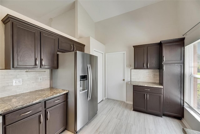 318 Lookout Dr, Apollo Beach, FL 33572 - kitchen with stainless steel fridge with ice dispenser, dark brown cabinets, high vaulted ceiling, tasteful backsplash, and light stone counters