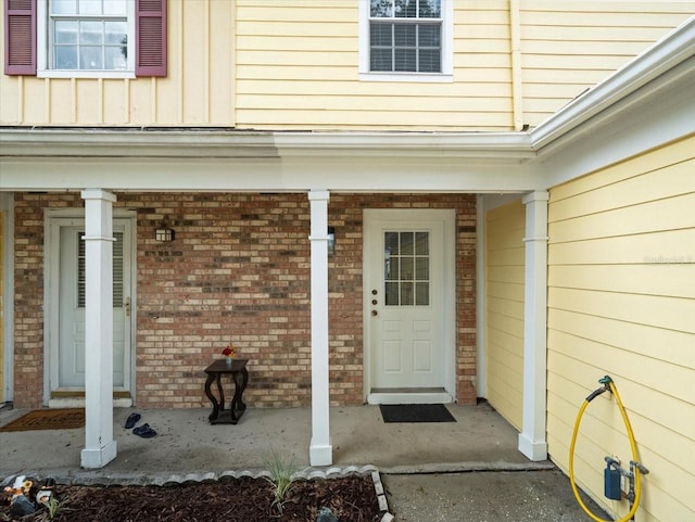 6114 Oak Cluster Cir, Tampa, FL 33634 - view of exterior entry featuring a porch, brick siding, and board and batten siding