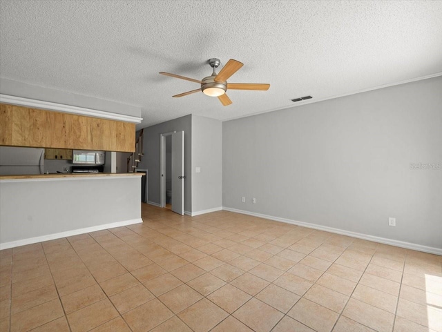 6114 Oak Cluster Cir, Tampa, FL 33634 - kitchen with stainless steel microwave, refrigerator, ceiling fan, a textured ceiling, and brown cabinetry