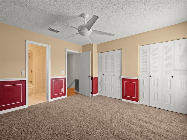 6114 Oak Cluster Cir, Tampa, FL 33634 - unfurnished bedroom with multiple closets, a wainscoted wall, carpet, a textured ceiling, and ceiling fan