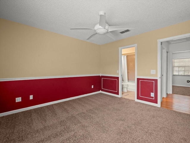 6114 Oak Cluster Cir, Tampa, FL 33634 - unfurnished bedroom with carpet, a textured ceiling, wainscoting, ensuite bath, and a ceiling fan