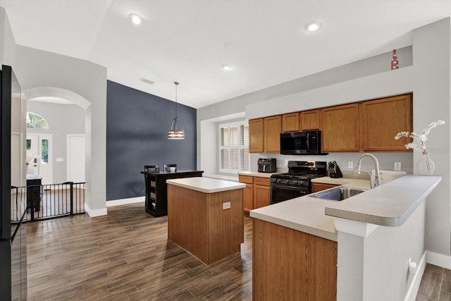 4901 Windingbrook Trl, Wesley Chapel, FL 33544 - kitchen with gas range oven, black microwave, arched walkways, light countertops, and brown cabinets