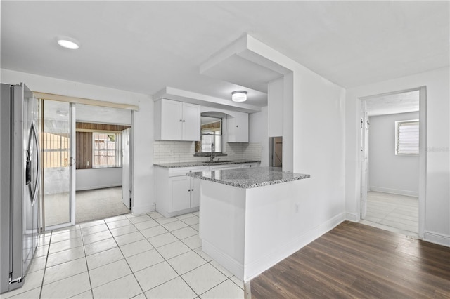 10730 Premier Ave, Port Richey, FL 34668 - kitchen featuring stainless steel refrigerator with ice dispenser, white cabinetry, light stone countertops, decorative backsplash, and plenty of natural light