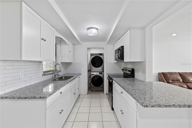 10730 Premier Ave, Port Richey, FL 34668 - kitchen with stainless steel range with electric cooktop, stacked washer / dryer, black microwave, tasteful backsplash, and white cabinets