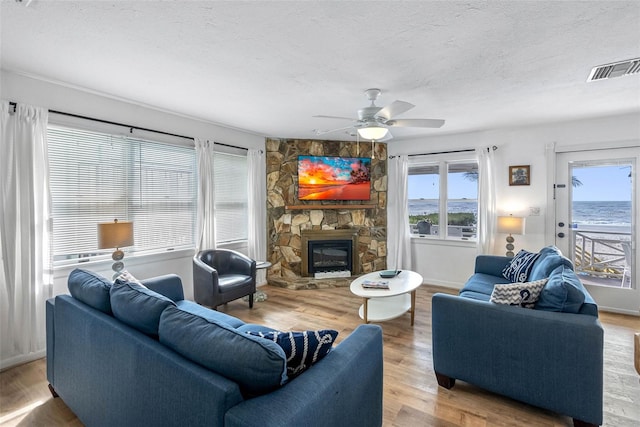 12458 1st St W, Treasure Island, FL 33706 - living room with a textured ceiling, wood finished floors, a fireplace, and a ceiling fan