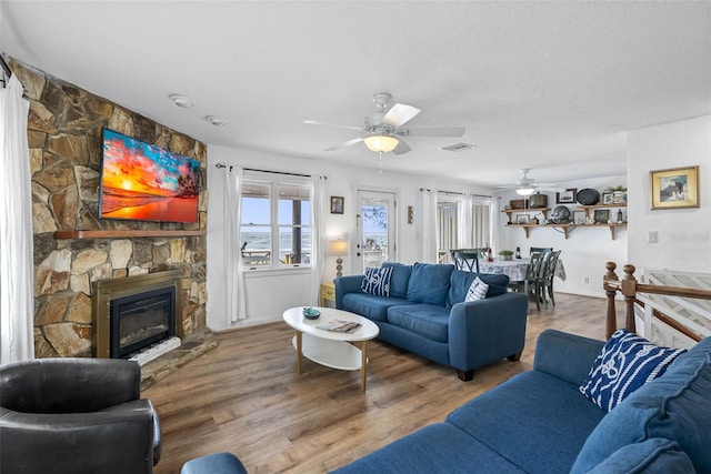 12458 1st St W, Treasure Island, FL 33706 - living room with a ceiling fan, wood finished floors, and a stone fireplace