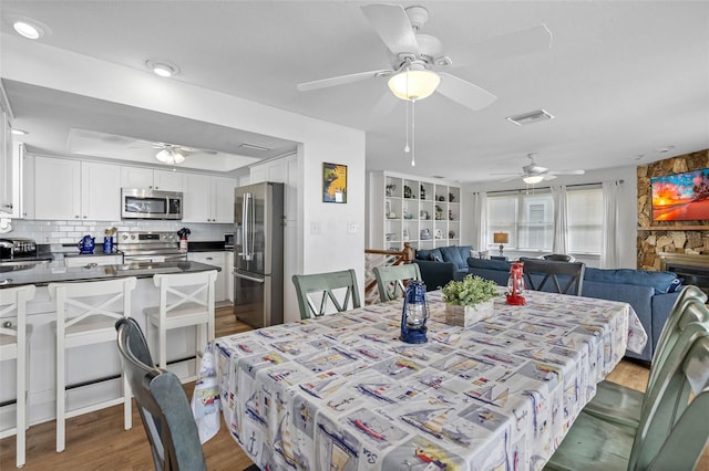 12458 1st St W, Treasure Island, FL 33706 - dining space featuring a ceiling fan, wood finished floors, and a fireplace