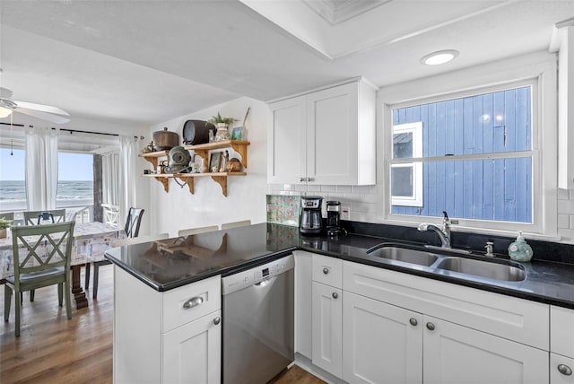 12458 1st St W, Treasure Island, FL 33706 - kitchen featuring stainless steel dishwasher, open shelves, dark countertops, white cabinets, and a peninsula