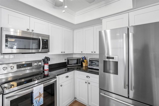 12458 1st St W, Treasure Island, FL 33706 - kitchen featuring appliances with stainless steel finishes, crown molding, white cabinetry, and tasteful backsplash