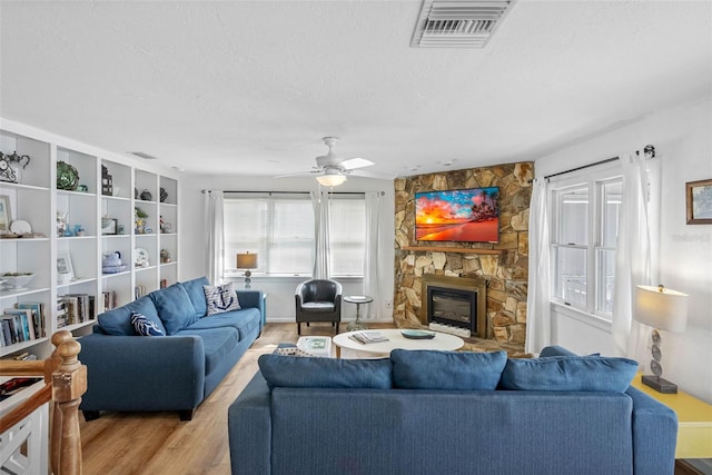 12458 1st St W, Treasure Island, FL 33706 - living area featuring a textured ceiling, a fireplace, light wood-style floors, and ceiling fan