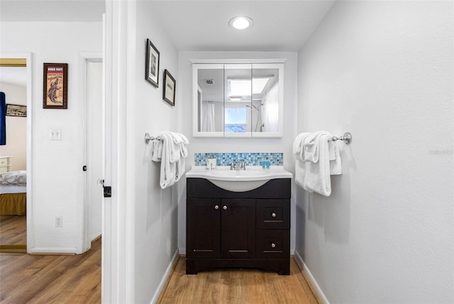 12458 1st St W, Treasure Island, FL 33706 - bathroom with vanity, wood finished floors, and backsplash