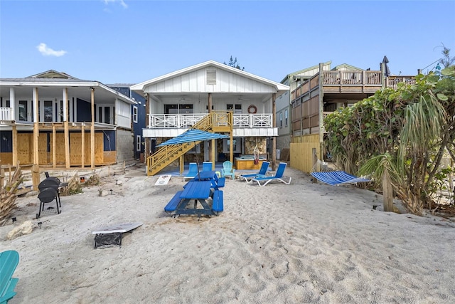 12458 1st St W, Treasure Island, FL 33706 - rear view of house featuring stairs, a hot tub, and board and batten siding