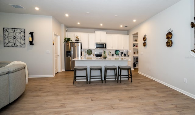 26082 Woven Wicker Bnd, Lutz, FL 33559 - kitchen featuring appliances with stainless steel finishes, a kitchen breakfast bar, white cabinets, recessed lighting, and a kitchen island with sink