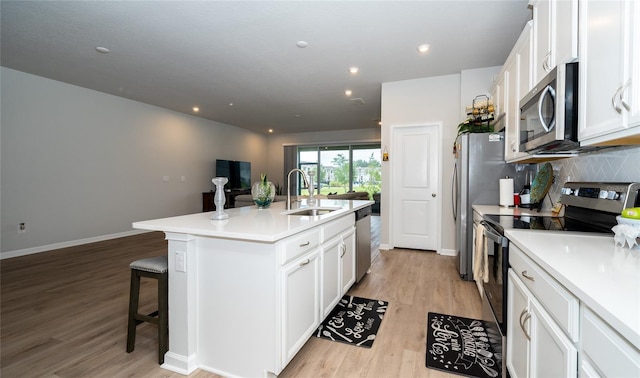 26082 Woven Wicker Bnd, Lutz, FL 33559 - kitchen featuring stainless steel appliances, a center island with sink, white cabinets, light wood-style floors, and recessed lighting