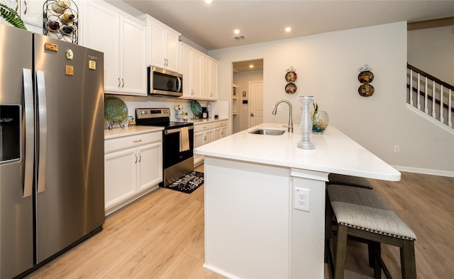 26082 Woven Wicker Bnd, Lutz, FL 33559 - kitchen featuring stainless steel appliances, a breakfast bar, light wood-style floors, white cabinets, and recessed lighting