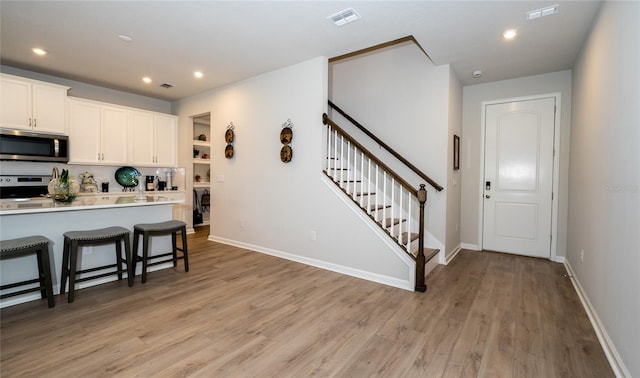 26082 Woven Wicker Bnd, Lutz, FL 33559 - kitchen with appliances with stainless steel finishes, a kitchen breakfast bar, white cabinetry, light wood-type flooring, and light countertops