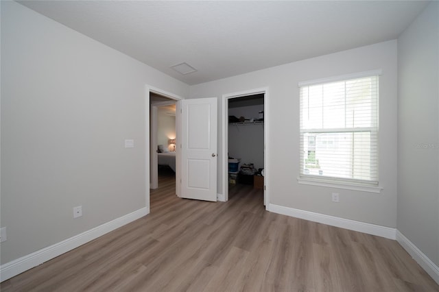 26082 Woven Wicker Bnd, Lutz, FL 33559 - unfurnished bedroom featuring light wood-style floors, a closet, and a walk in closet