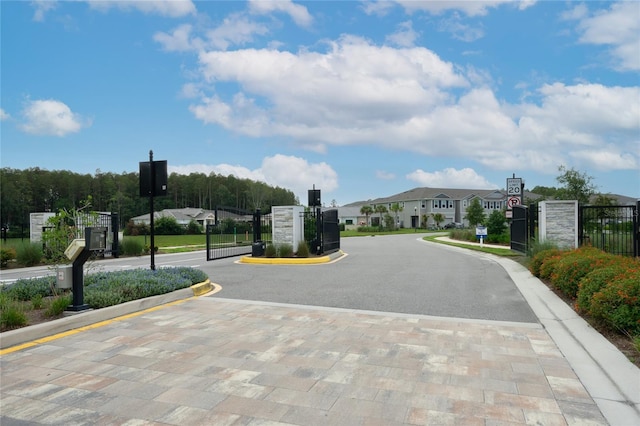 26082 Woven Wicker Bnd, Lutz, FL 33559 - view of asphalt street featuring traffic signs, curbs, a gated entry, and a residential view